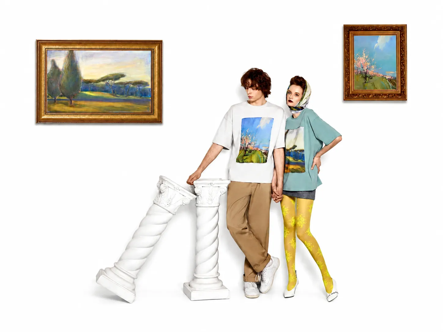 Two models wearing matching art-print T-shirts beside the original framed painting